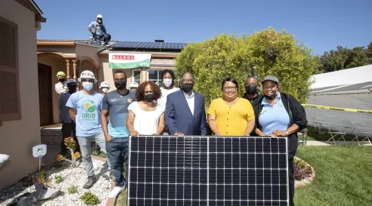 Group photo standing behind solar panel