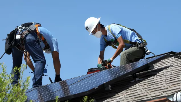 workers installing solar panel on resident's home
